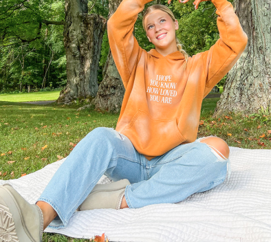 Person in orange hoodie sitting outdoors